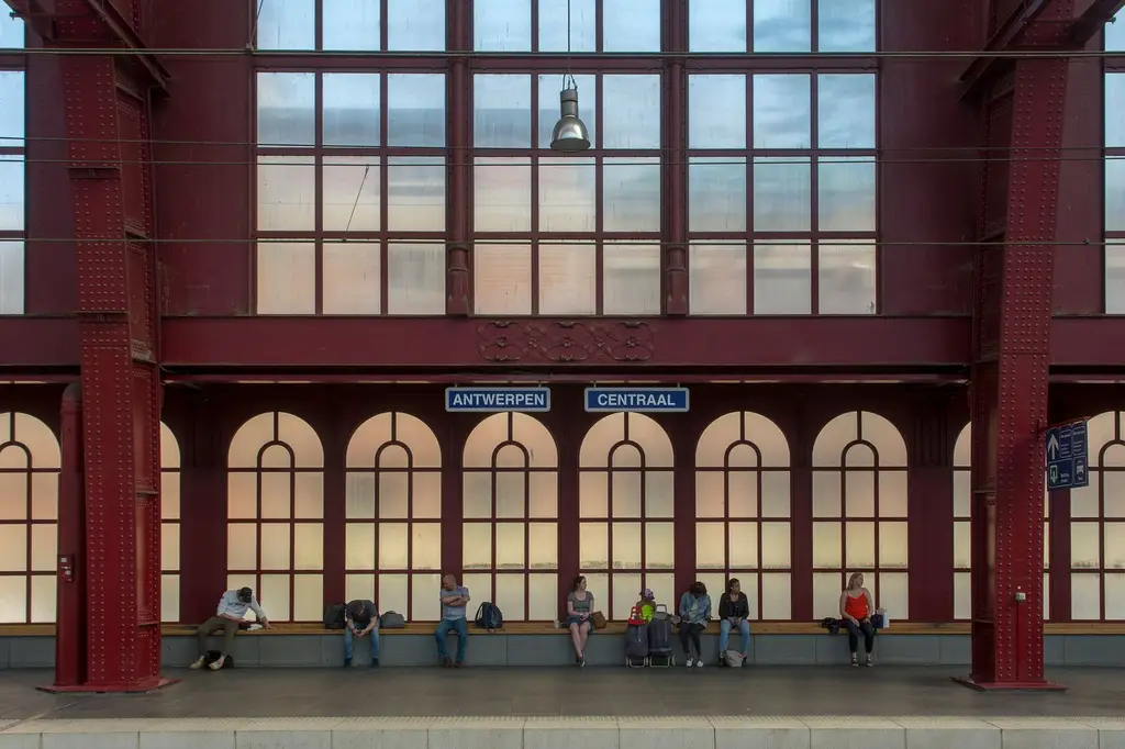 Commuters sitting and waiting at Antwerp's central railway station platform.