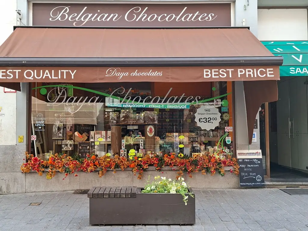 Colorful street view of a delightful Belgian chocolate shop with floral decorations in Bruges.