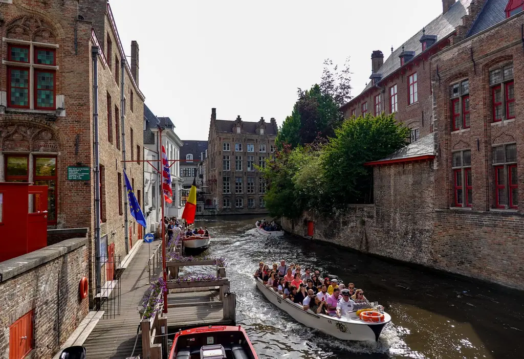 A scenic view of tourists enjoying a boat ride through the historic canals of Bruges, Belgium.