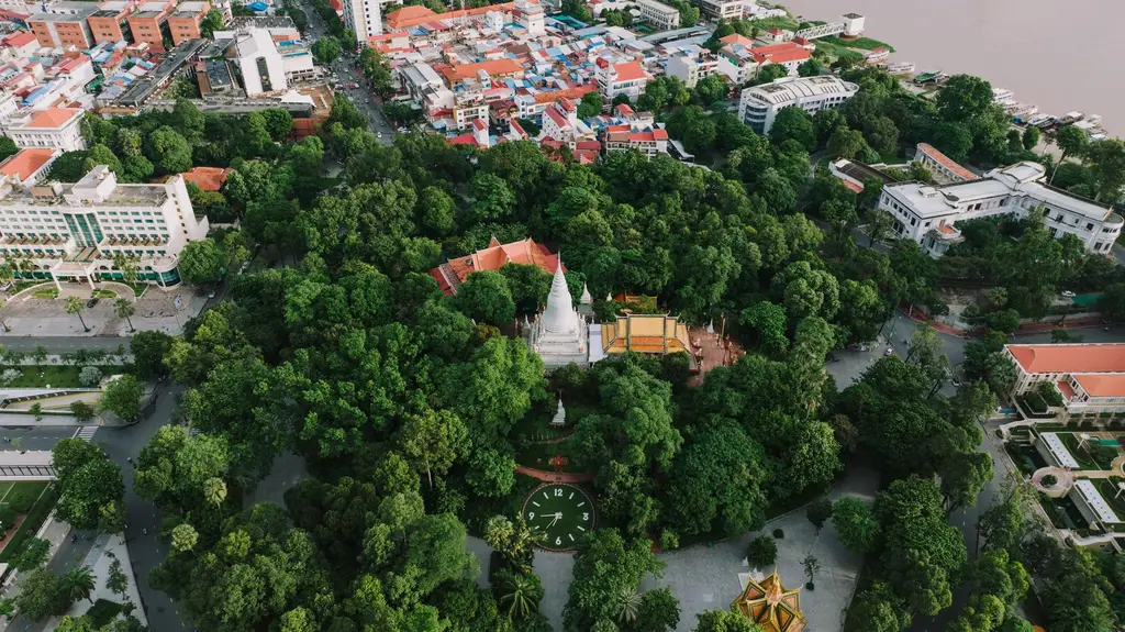 A vibrant aerial view of Wat Phnom, surrounded by lush greenery in Phnom Penh, Cambodia, capturing its significance and cityscape.