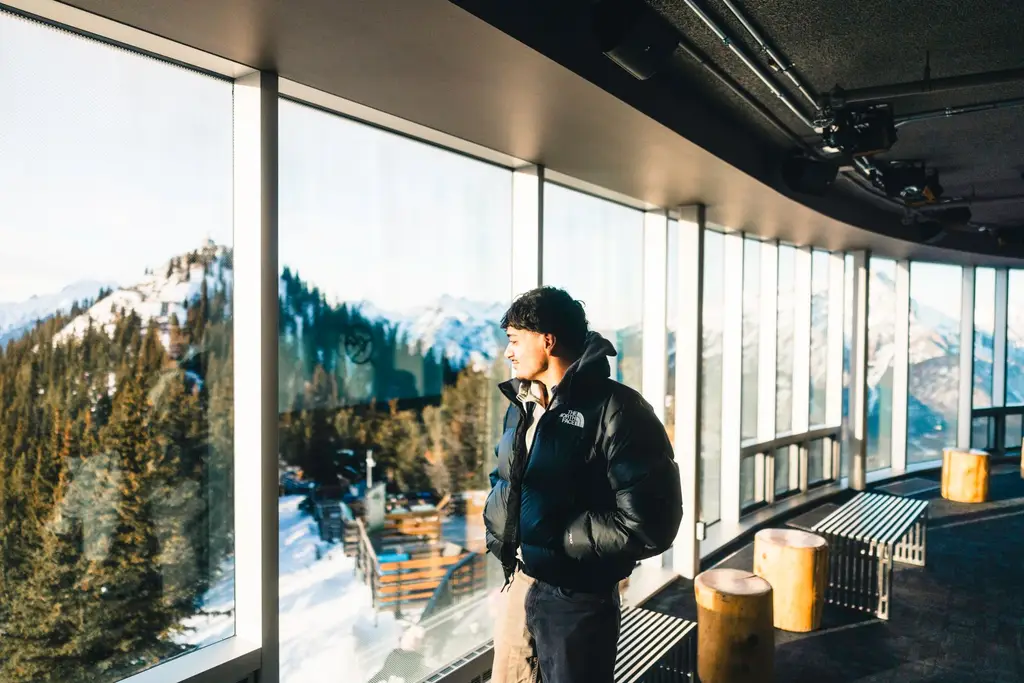 Man enjoying scenic winter mountain view from Banff Gondola in Alberta, Canada.