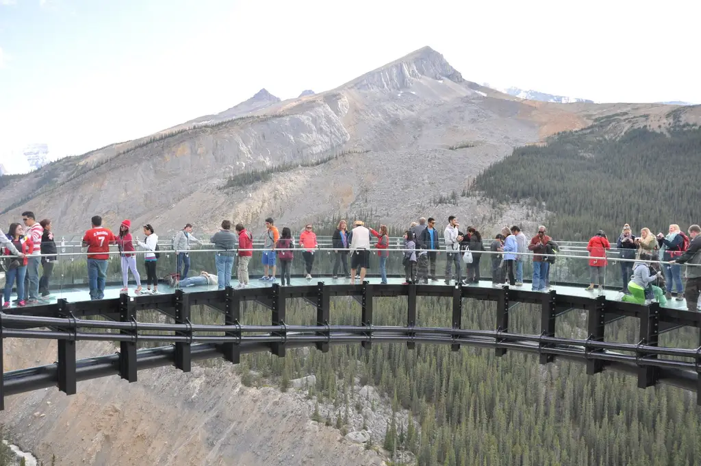 Tourists enjoying the breathtaking view from the Columbia Icefield Skywalk in Alberta, Canada.