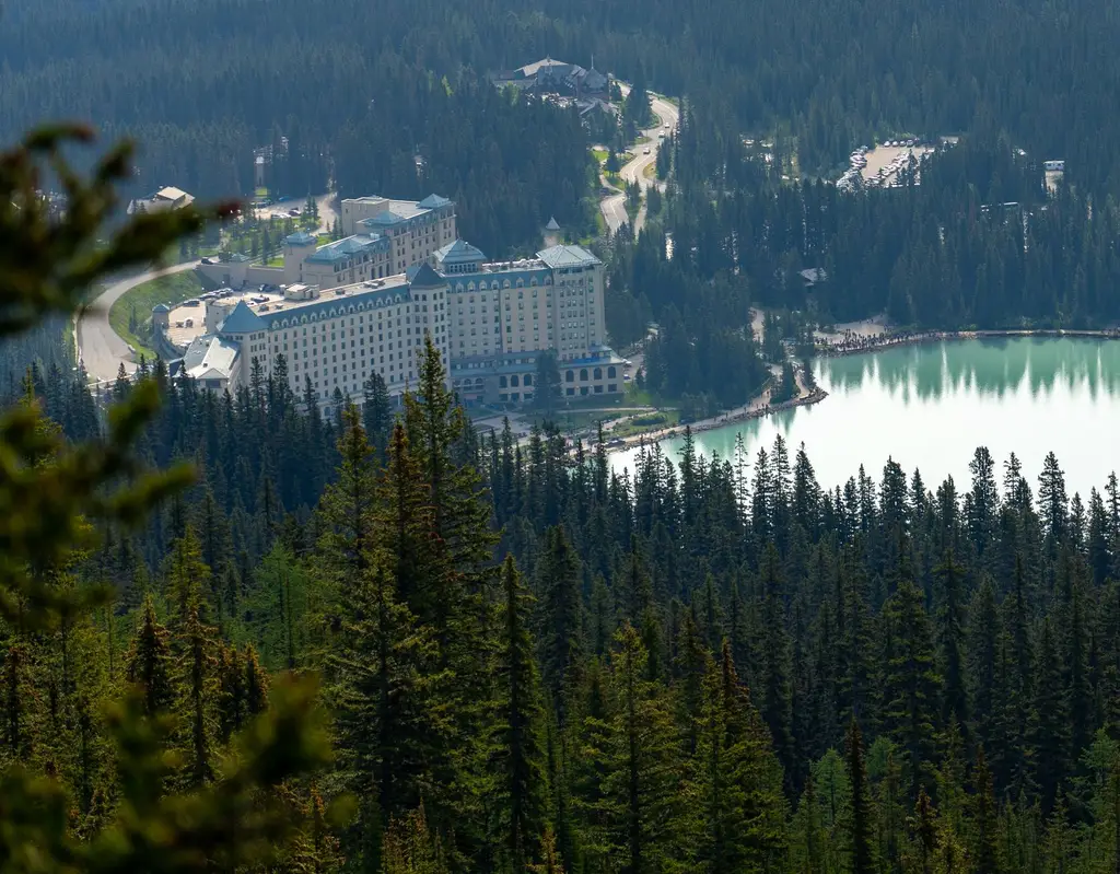 Stunning aerial shot of Fairmont Chateau Lake Louise surrounded by lush forests and a picturesque lake.