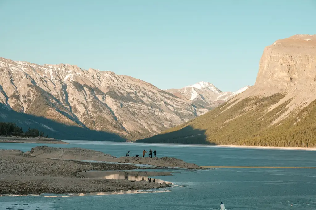 A group enjoys the breathtaking view at Lake Minnewanka in Banff, surrounded by the majestic Canadian Rockies.