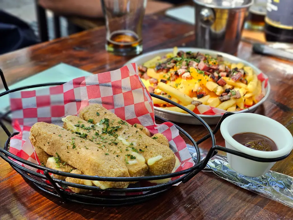 Crispy cheese sticks and loaded poutine served on a rustic outdoor setting.