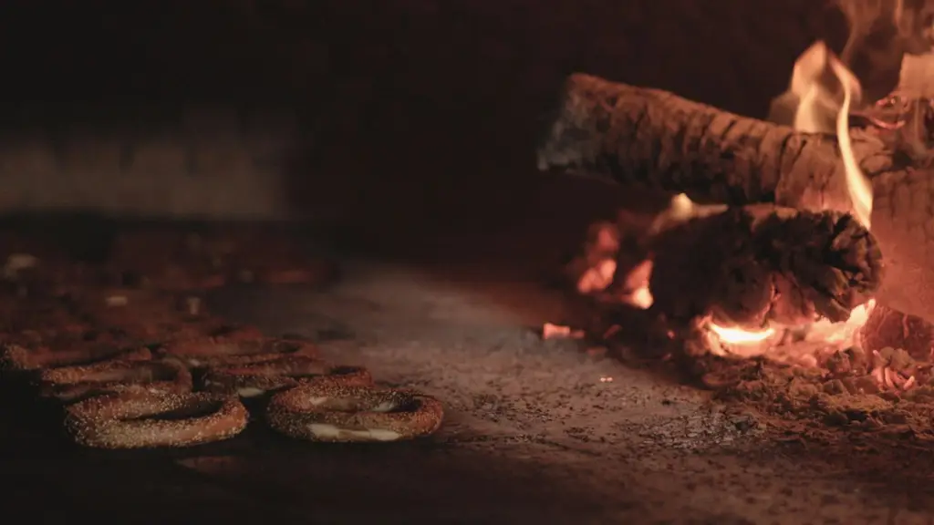 Rustic bagels baking in a traditional wood-fired oven with glowing flames.