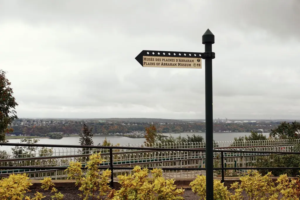 Scenic view of the Plains of Abraham in Quebec City during autumn with a directional sign.