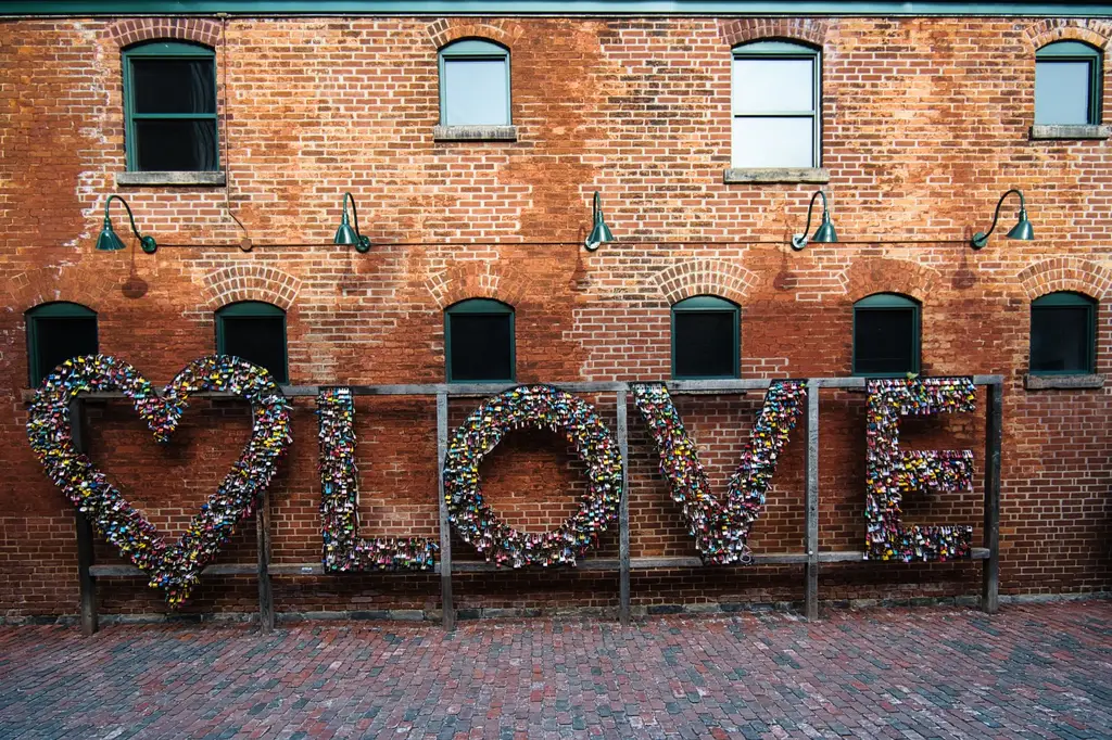 Heart-shaped love lock wall against a vintage red brick facade in Toronto's Distillery District.