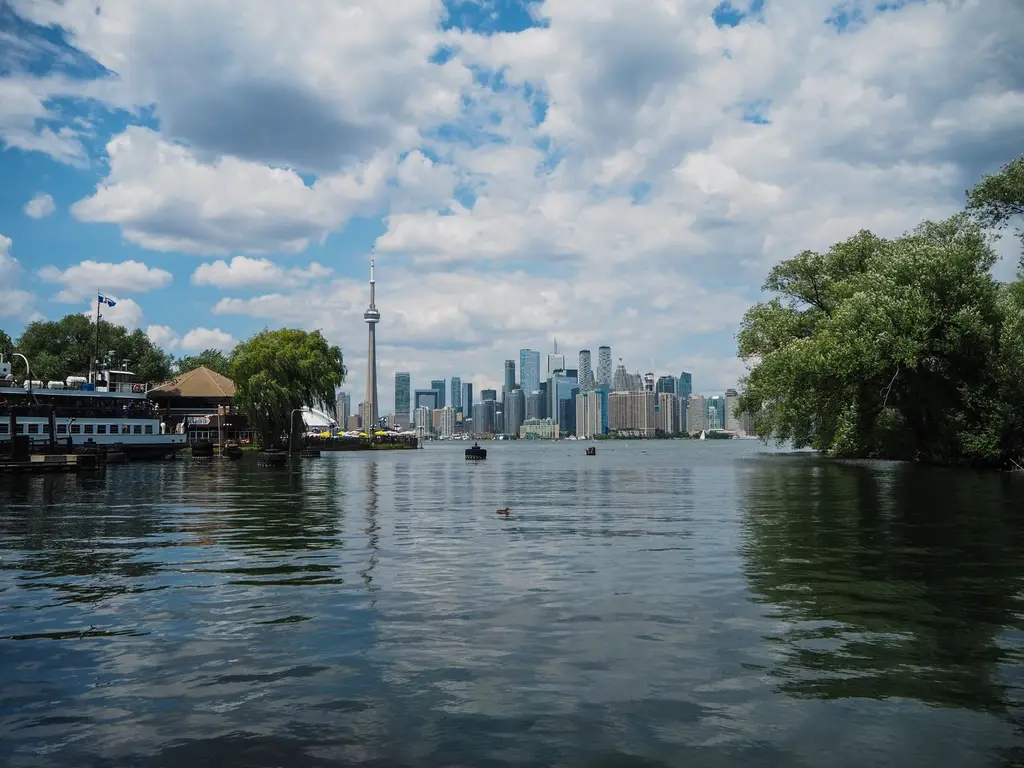 Scenic view of Toronto skyline with CN Tower from the water, under a vibrant summer sky.