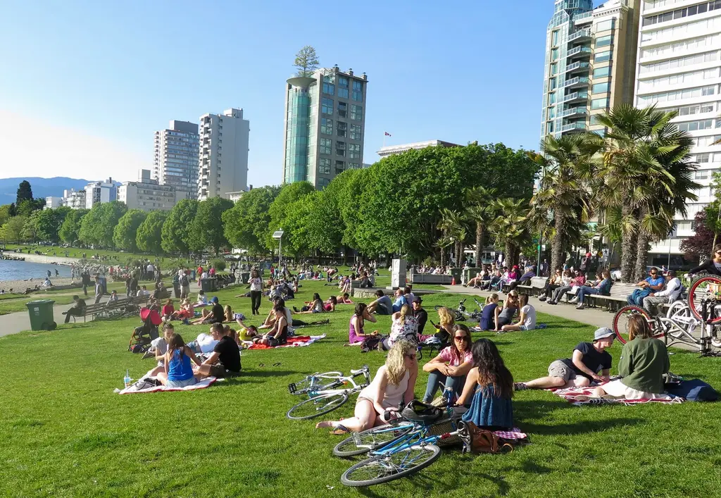 People enjoy a sunny day at English Bay Park, Vancouver, Canada.