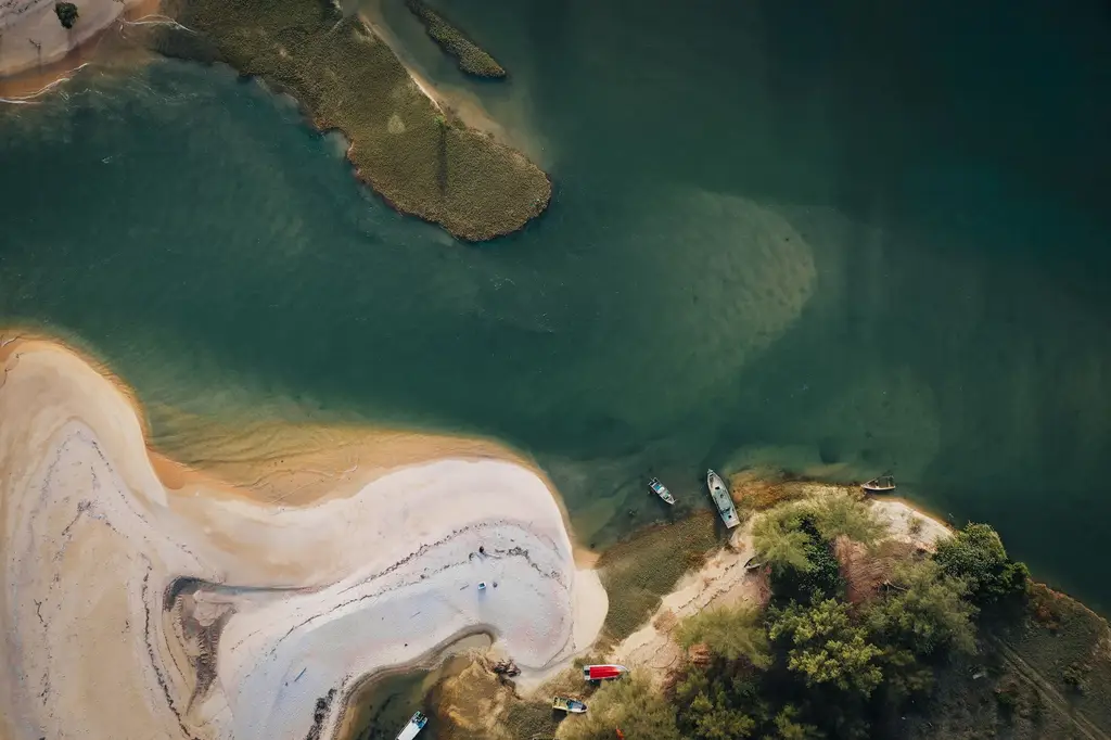A stunning aerial view of Kemasik beach and estuary featuring boats and surrounding greenery.