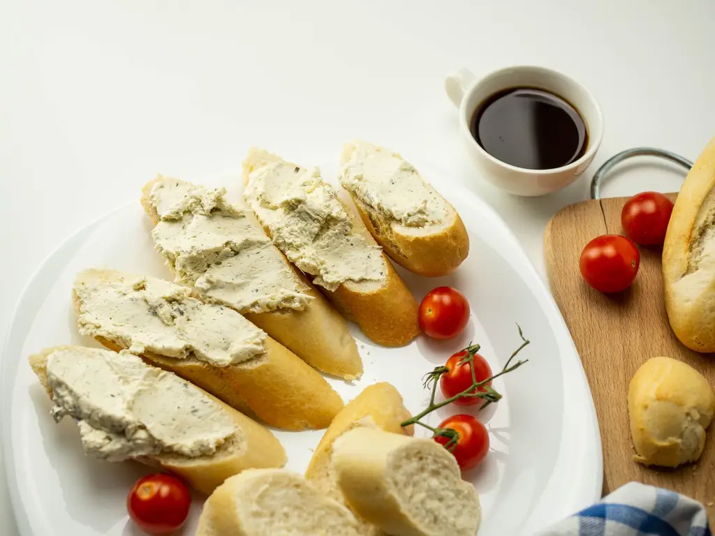 Delicious breakfast setup with bread, cheese spread, cherry tomatoes, and a cup of coffee.