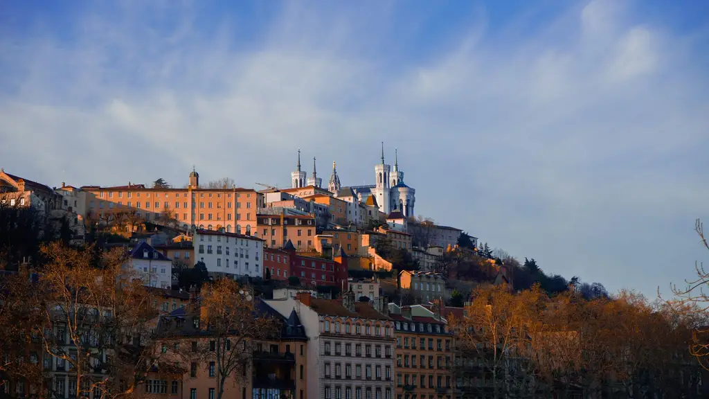 A scenic view of Lyon's historic old town and Basilica of Notre-Dame de Fourvière basking in the warm evening light.