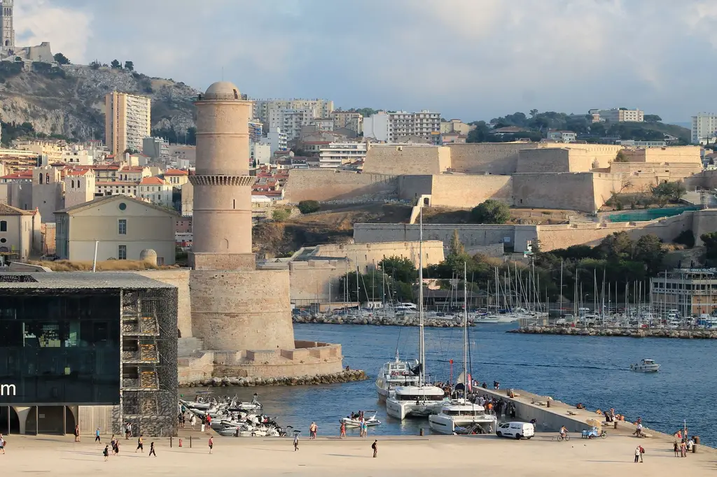 Scenic view of Marseille's historic Fort Saint-Jean and vibrant harbor in France, capturing urban architecture and waterfront activity.