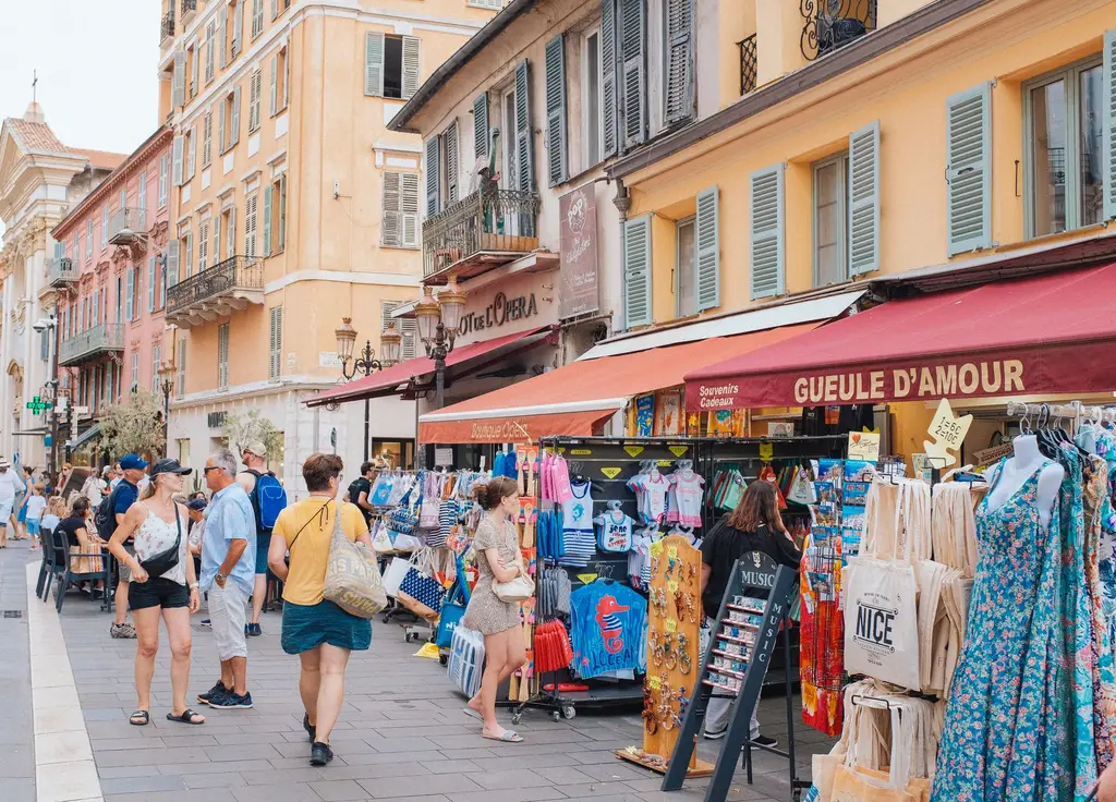 Street market scene in Nice, France with shoppers and colorful storefronts.