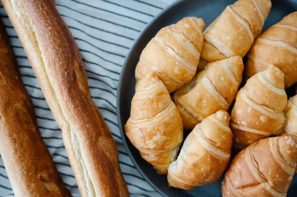 Fresh croissants and baguettes displayed on a striped tablecloth, perfect for breakfast or brunch visuals.