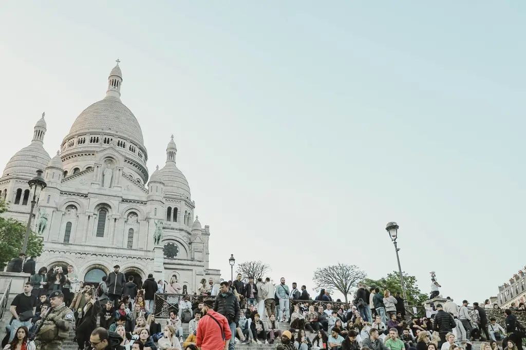 View of Sacre-Coeur Basilica with a large crowd on steps in Montmartre, Paris.