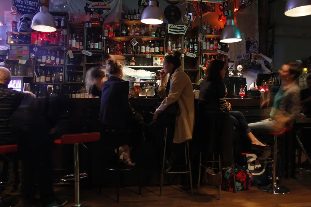 Cozy Parisian bar with people enjoying drinks and socializing at night.