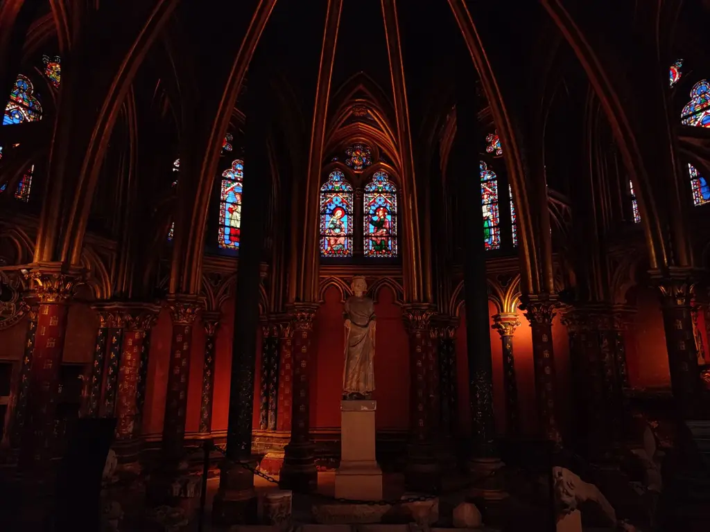 Gothic interior of Sainte-Chapelle in Paris with vibrant stained glass windows and sculptures.