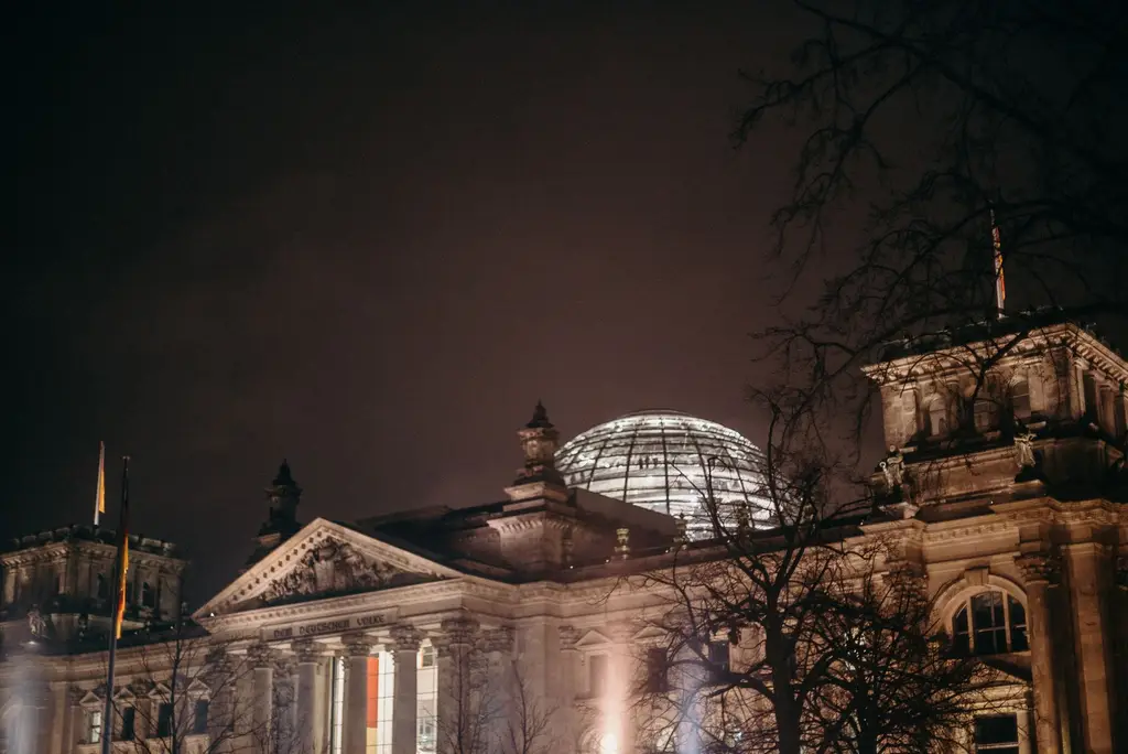 Illuminated Reichstag building at night, showcasing its iconic glass dome in Berlin, Germany.