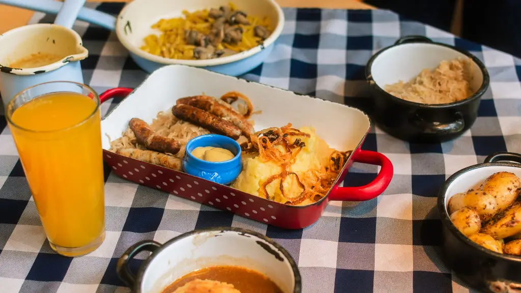 Tasty lunch with sausages, mashed potatoes, and sides on a checkered cloth.