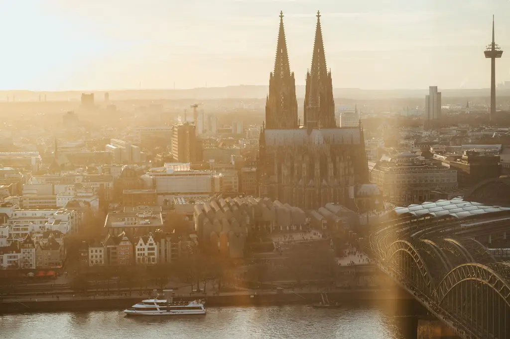 Aerial view of Cologne Cathedral with golden sunrise over the Rhine River.