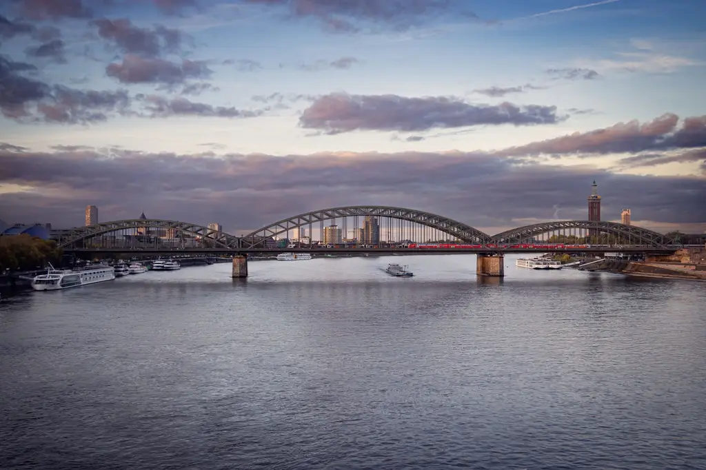 Aerial view of the Hohenzollern Bridge and Rhine River in Cologne, Germany at dusk.