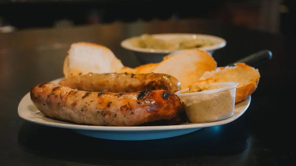 Delicious grilled sausages served with fresh bread and mustard on a white plate.
