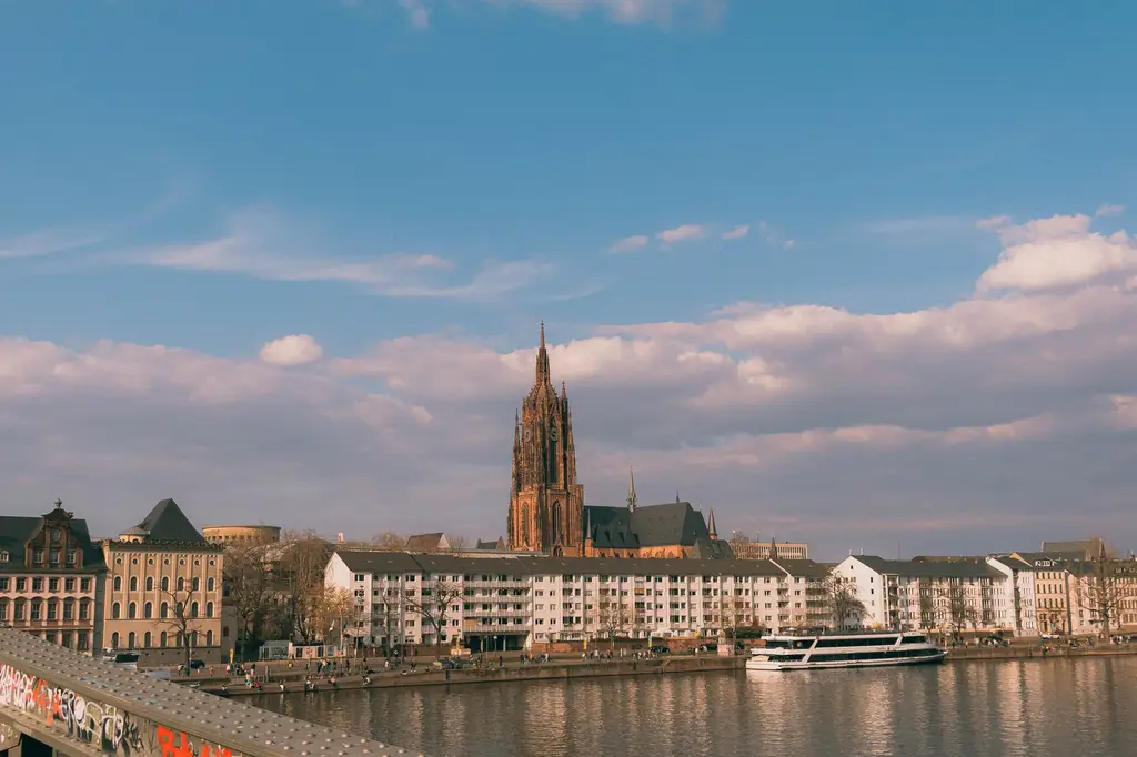 Scenic view of Frankfurt Cathedral and Main River at sunset showcasing city architecture and serene waters.