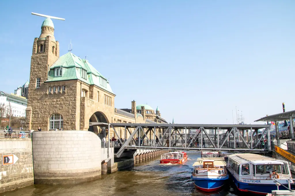 Vibrant view of the iconic Landungsbrücken Pier with boats on the Elbe River, Hamburg.