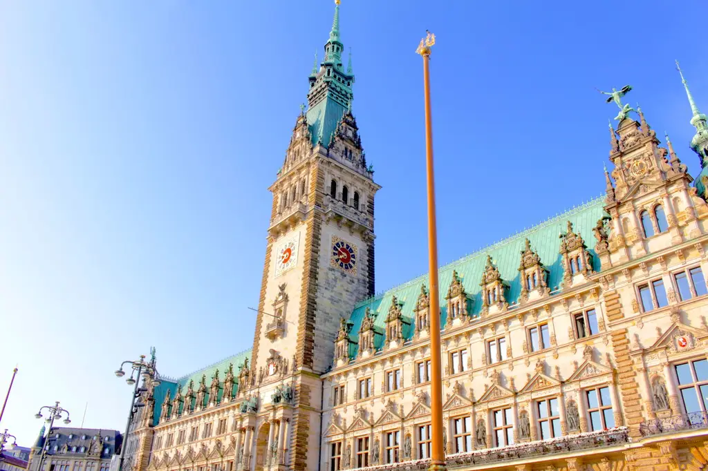 Architectural view of Hamburg City Hall clock tower under a clear blue sky.