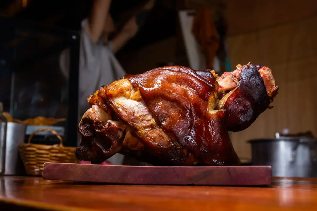 Close-up of a crispy roasted pork knuckle on a wooden cutting board, perfect for stock imagery.