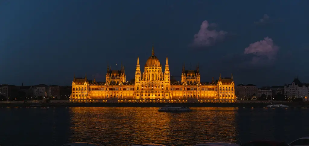 Night view of the glowing Hungarian Parliament Building reflected in the Danube River.