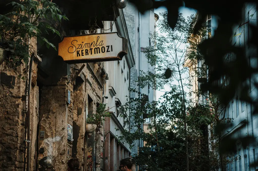 A vintage alleyway scene showing Szimpla Kertmozi sign amidst Budapest's ruin pubs.