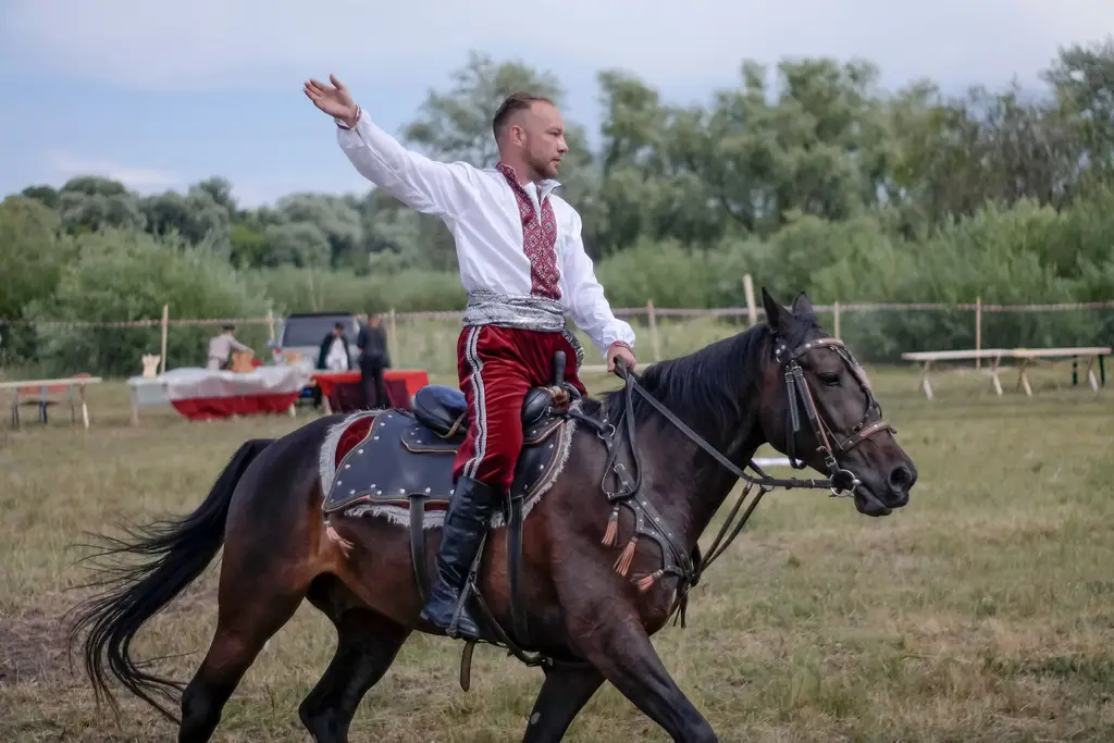 A man in traditional attire rides a horse during an outdoor cultural festival.