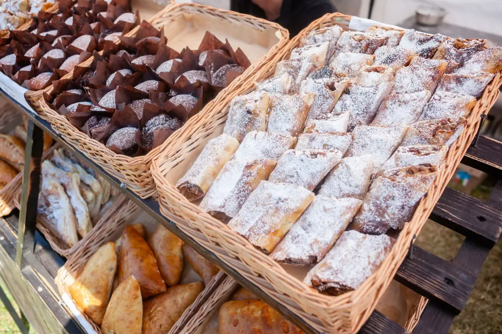 A variety of fresh pastries, including strudels and muffins, arranged in wicker baskets at a market display.