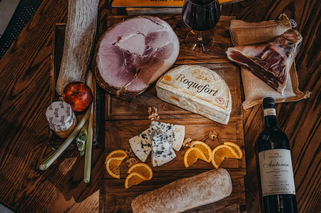 Top view of a gourmet charcuterie board with wine, cheese, and cured meats on a rustic wooden table.