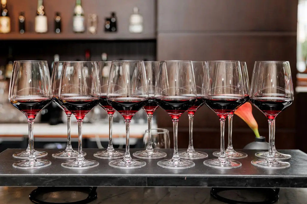 A row of red wine glasses elegantly arranged on a bar counter, creating a sophisticated ambience.