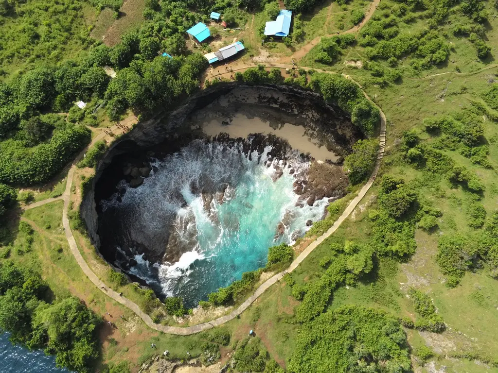 A breathtaking aerial view of Angel's Billabong in Nusa Penida, Bali showcasing vibrant turquoise waters in a rocky inlet.