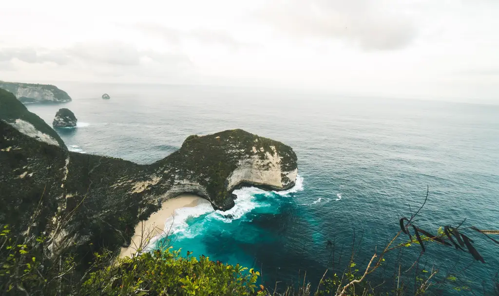 Stunning aerial view over Kelingking Beach on Nusa Penida, showcasing cliffs and turquoise ocean waters.