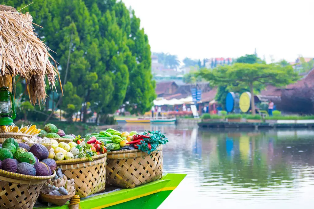 Colorful display of tropical fruits and vegetables at a floating market by a scenic lakeside.