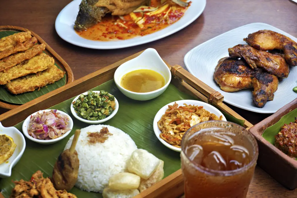 A vibrant display of traditional Indonesian cuisine featuring rice, fried chicken, and more on banana leaves.