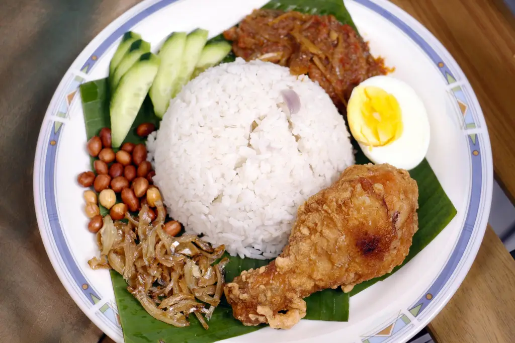 A vibrant plate of traditional Nasi Lemak with rice, fried chicken, egg, and sambal.