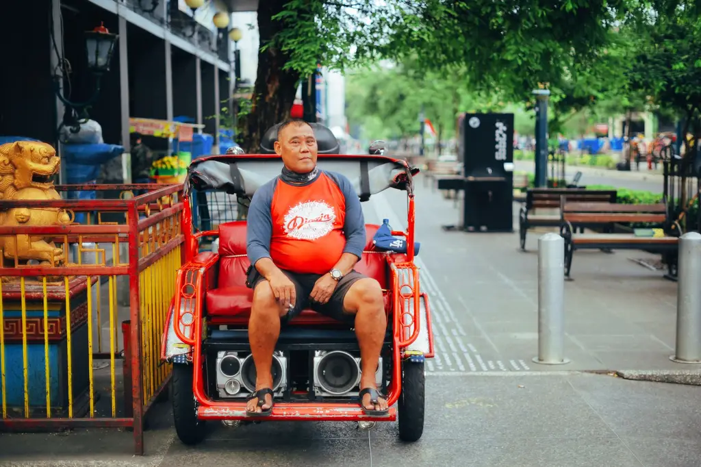 A man sitting on a rickshaw in the vibrant streets of Yogyakarta, Indonesia.