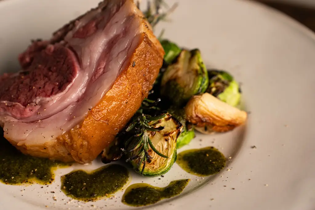 A close-up of gourmet roasted lamb served with Brussels sprouts and rosemary in a fine dining setting.