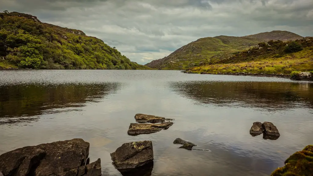 Serene view of a lake surrounded by lush green hills in Killarney National Park, Ireland.