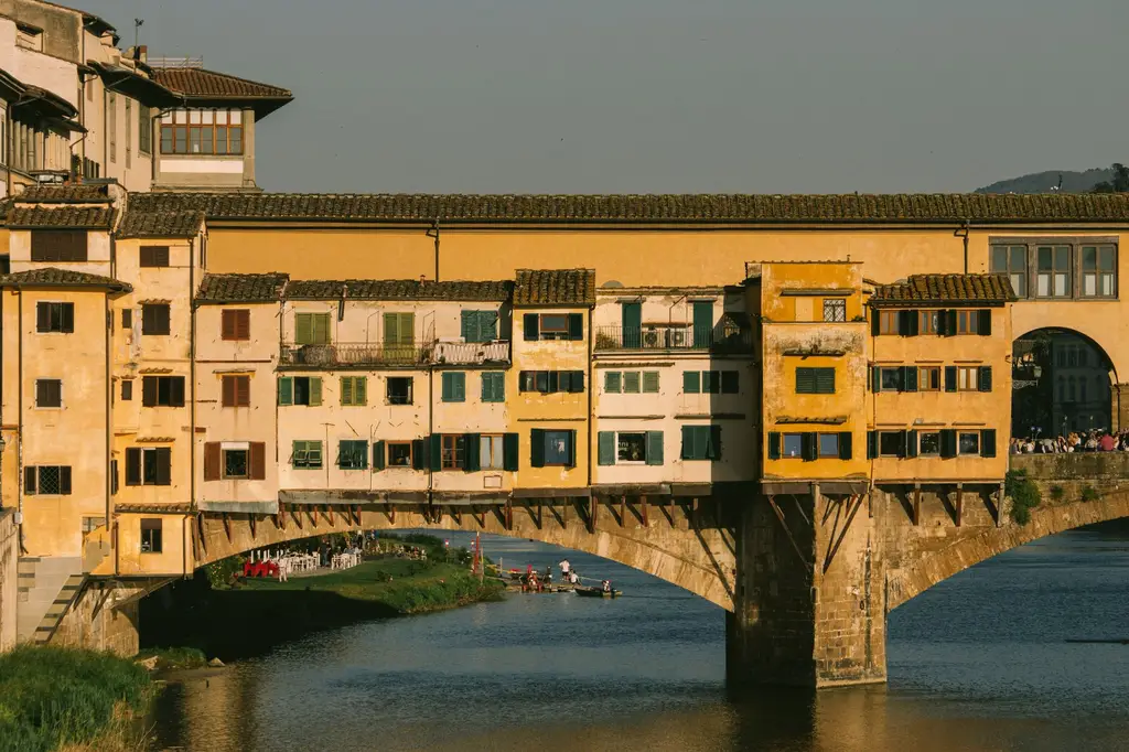 Ponte Vecchio in Florence glowing in golden hour sunlight over the Arno River.