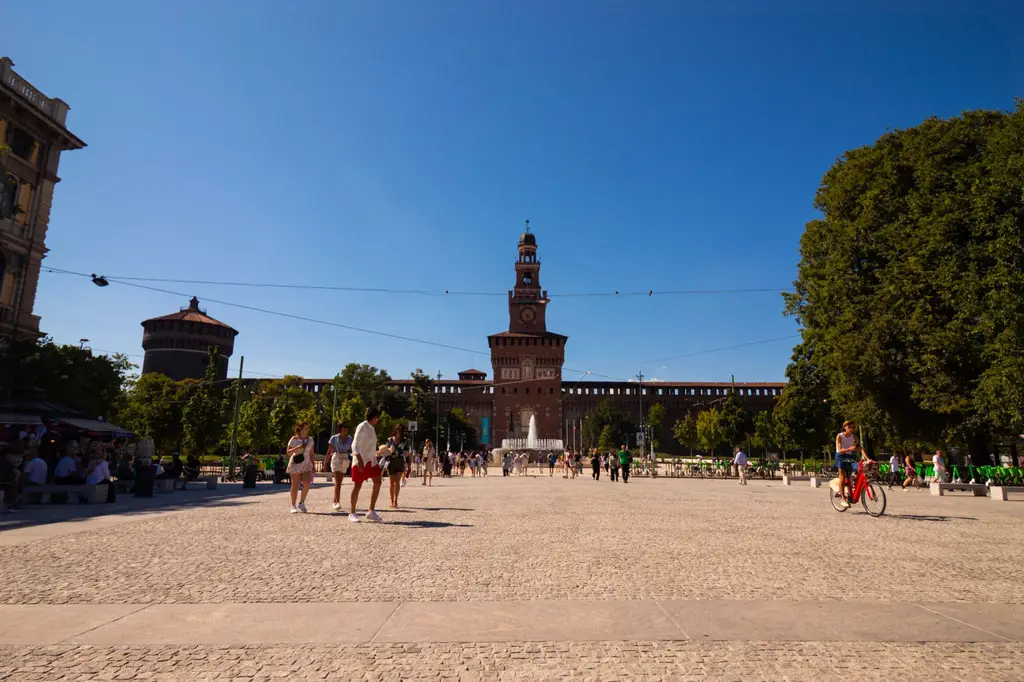 People enjoying a sunny day at Sforza Castle in Milan, Italy, a historical landmark with vibrant surroundings.