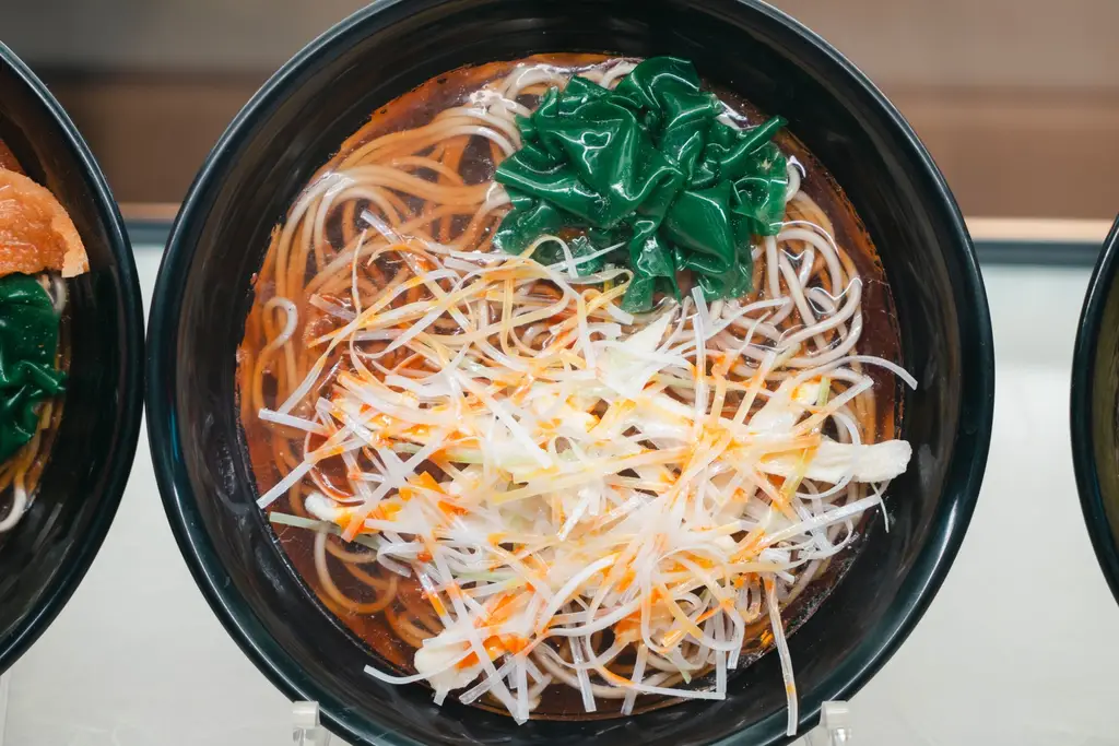 Top view of a ramen bowl with noodles, spinach, and toppings, captured in Tokyo, Japan.