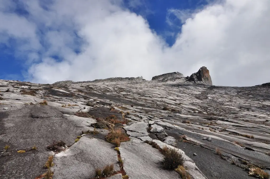 Stunning landscape of Mount Kinabalu's rocky summit under a clear blue sky in Malaysia.